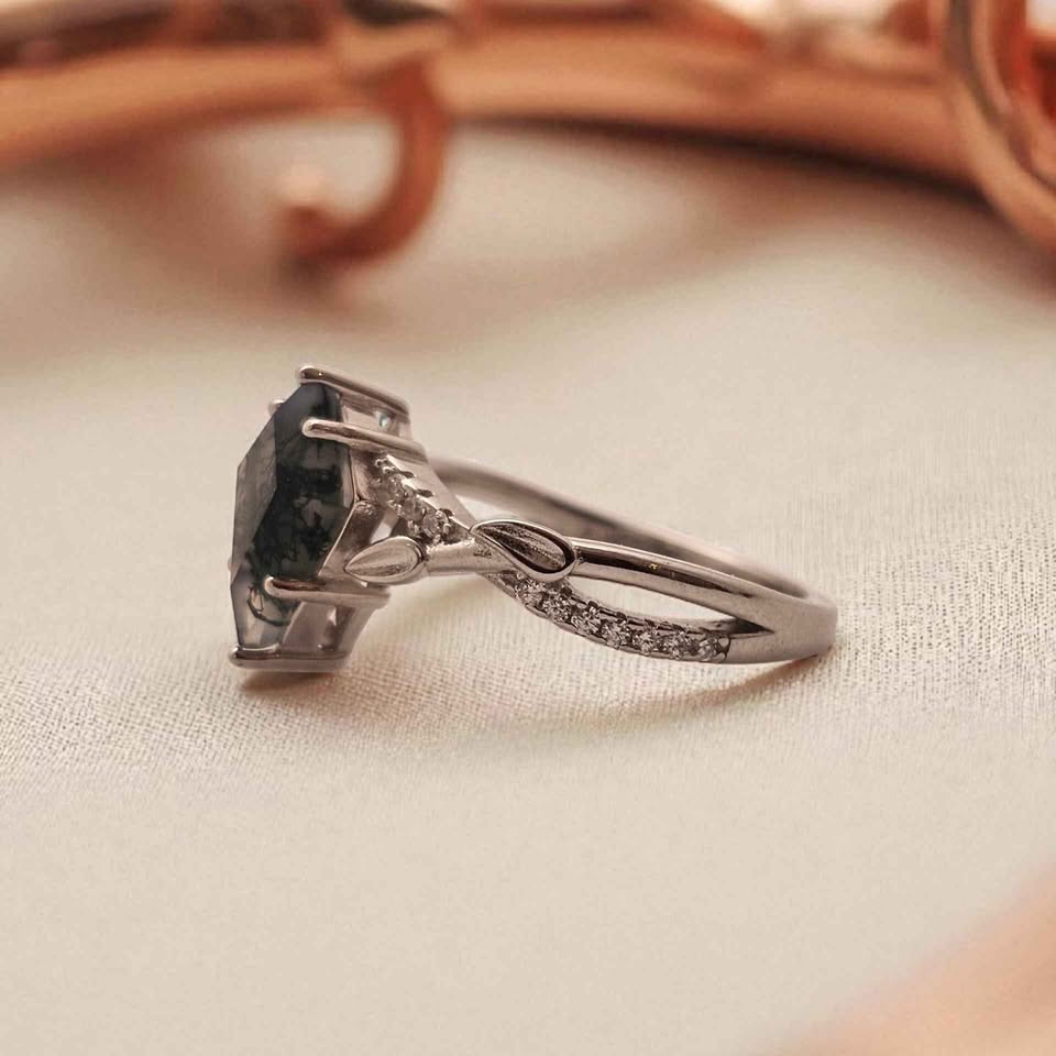 Side view of kite cut Moss Agate ring set in 925 sterling silver with 18k white gold plating, showcasing prong setting, leaf detail, and cubic zirconia accents on elegant band