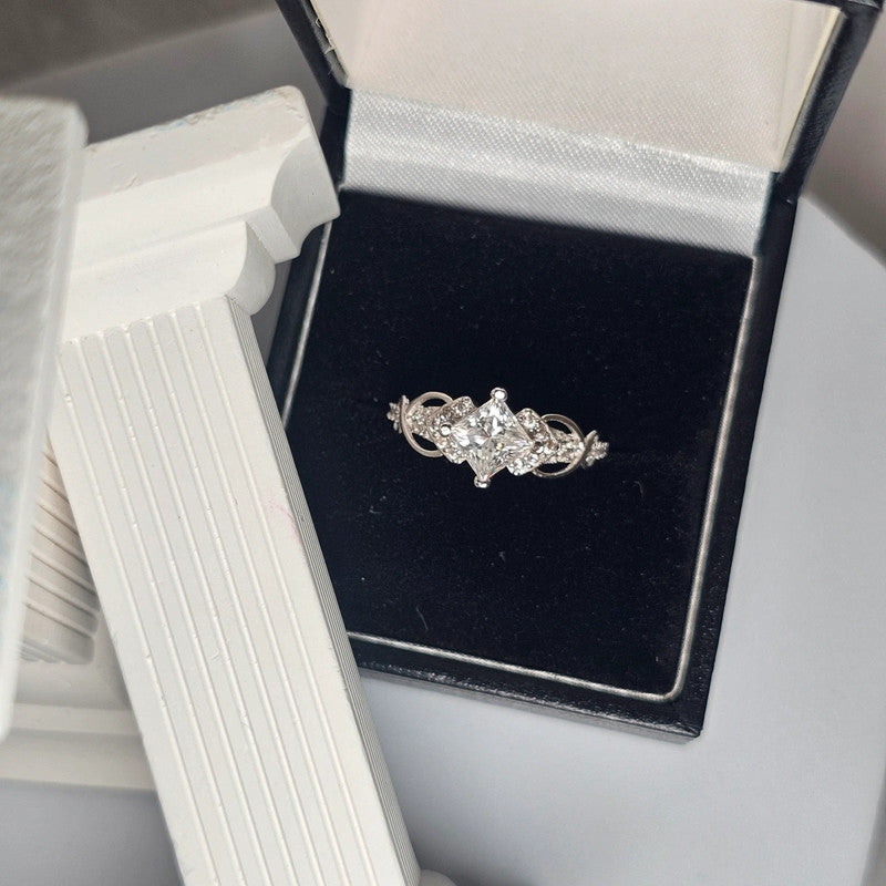 Moissanite sterling silver ring with brilliant-cut center stone and accent stones displayed in black velvet jewelry box
