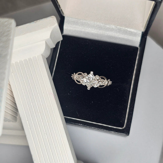 Moissanite sterling silver ring with brilliant-cut center stone and accent stones displayed in black velvet jewelry box