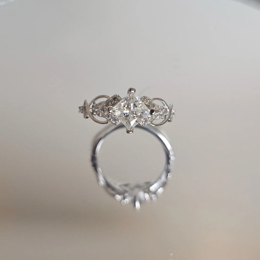 Side view of moissanite sterling silver ring with marquise accent stones and prong-set brilliant-cut center stone on reflective surface