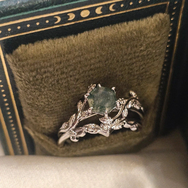 Silver ring with green gemstone in a decorative box