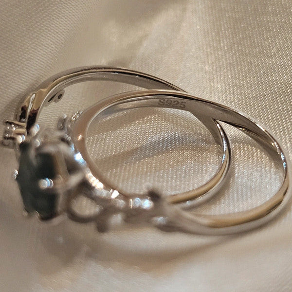 Silver ring with a dark gemstone on a beige fabric background