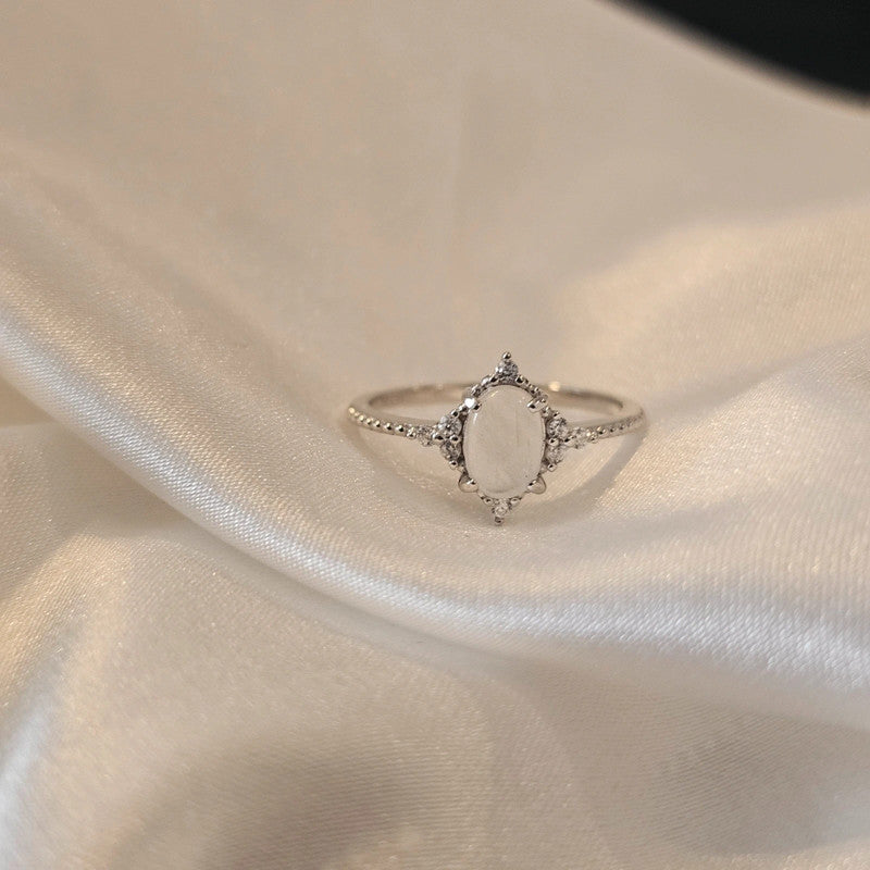 Silver moon stone ring with a cubic zirconia accent stones on a beige fabric background