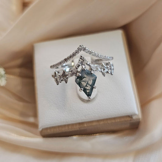 Faewood Crown moss agate engagement ring set featuring kite-shaped moss agate center stone and crown band with accent stones displayed on white ring box and satin backdrop