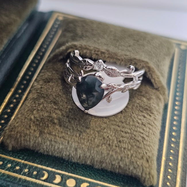 Moss agate and cubic zirconia ring resting on green cushioned jewelry stand inside vintage box