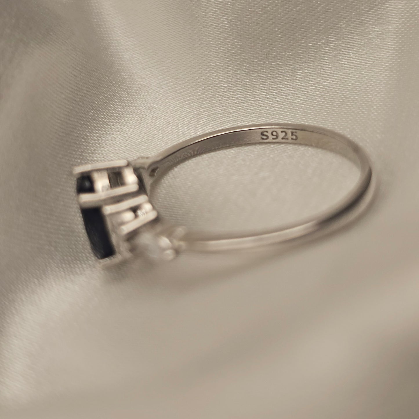 Silver ring with '925' stamp on a beige fabric background