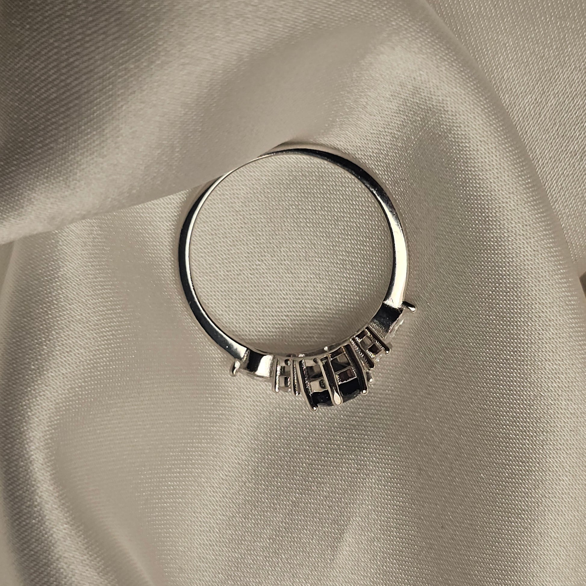 Silver ring with a textured band on a beige fabric background