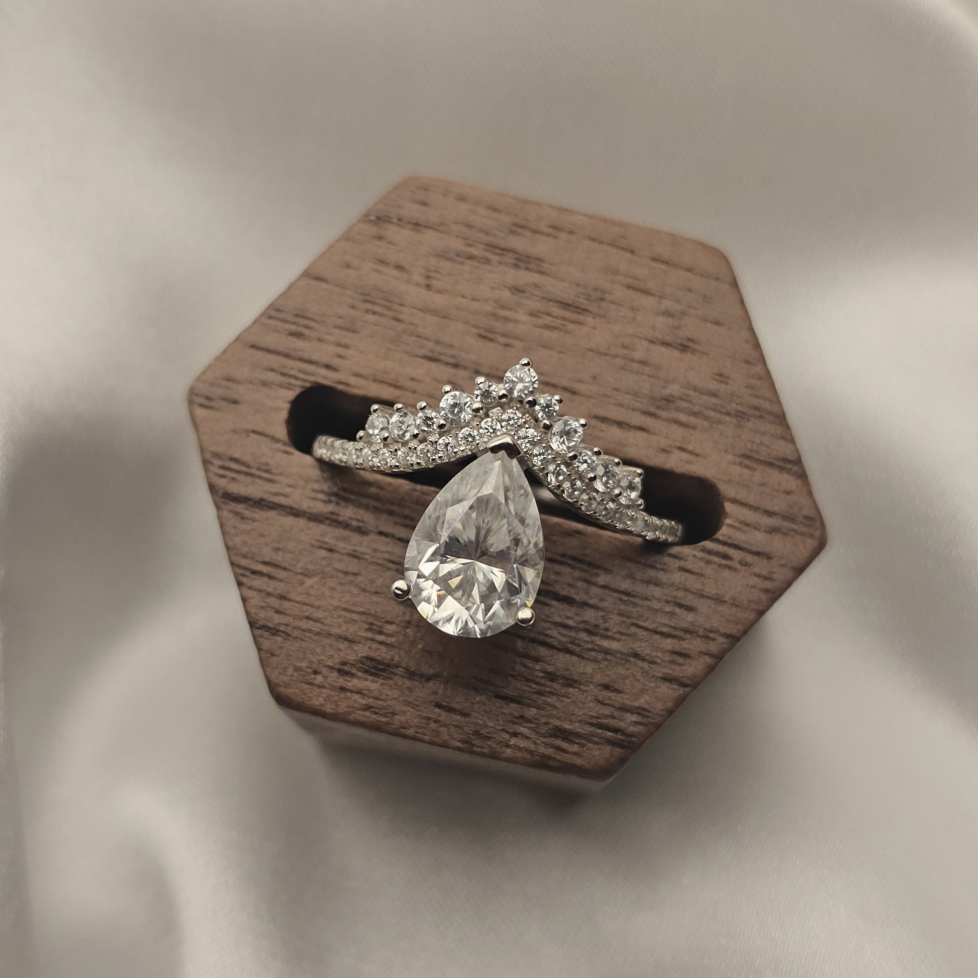 Diamond ring on a wooden hexagonal stand against a beige fabric background