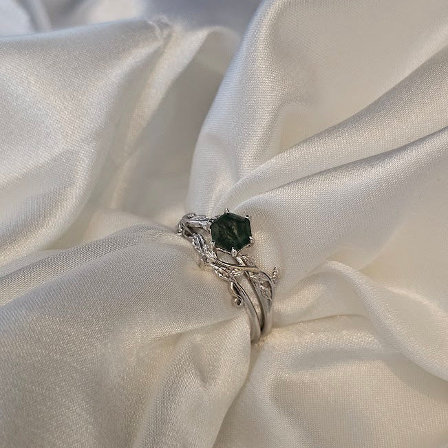 Silver ring with a black gemstone on a white satin fabric