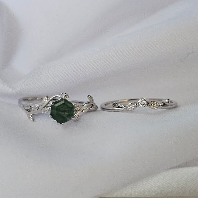 Silver ring with a green gemstone on a white fabric background