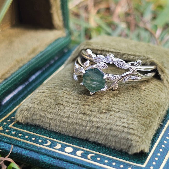 Silver ring with green gemstone on a green cushion inside an open book