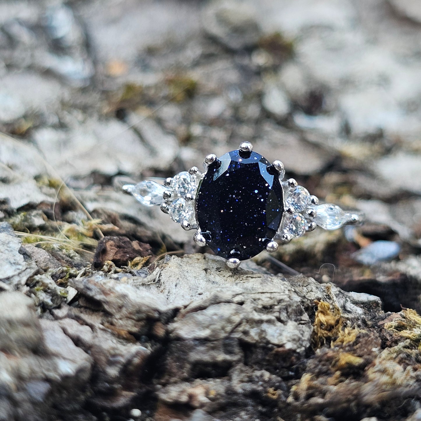 Black stone ring with silver setting on a textured stone background