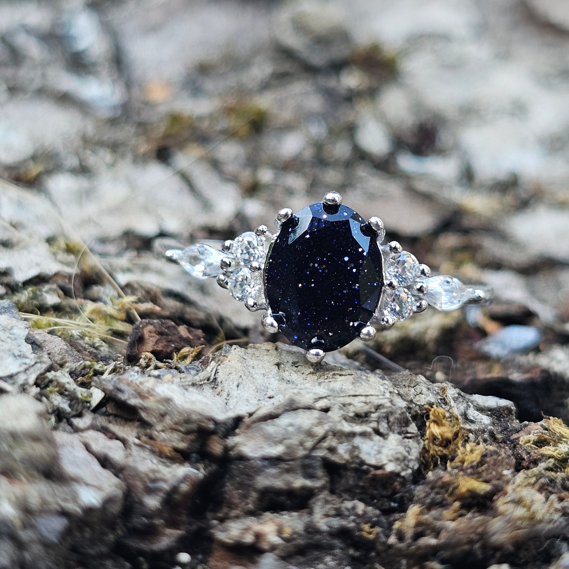Black stone ring with silver setting on a textured stone background