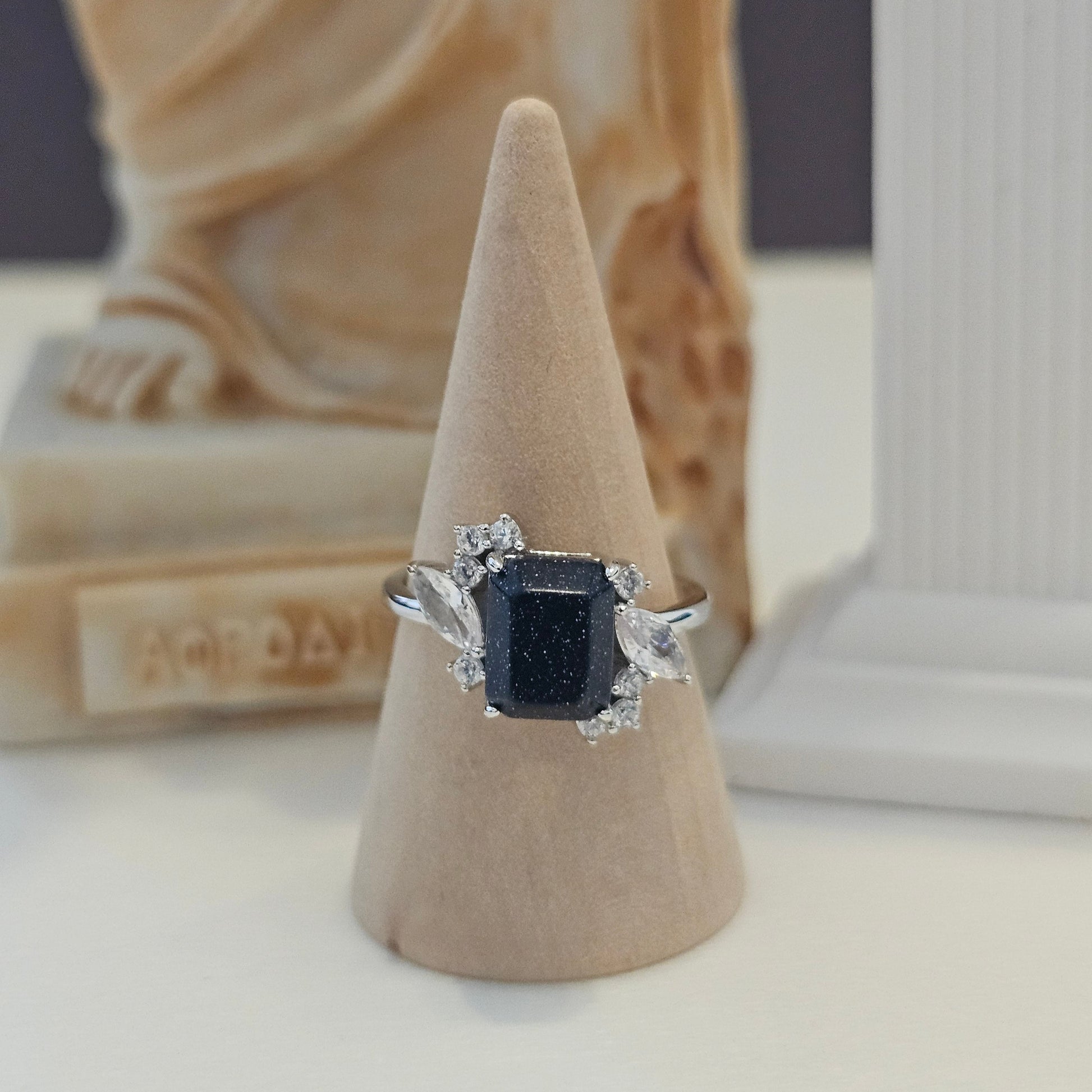 Ring with a prominent gemstone on a beige stand against a neutral background