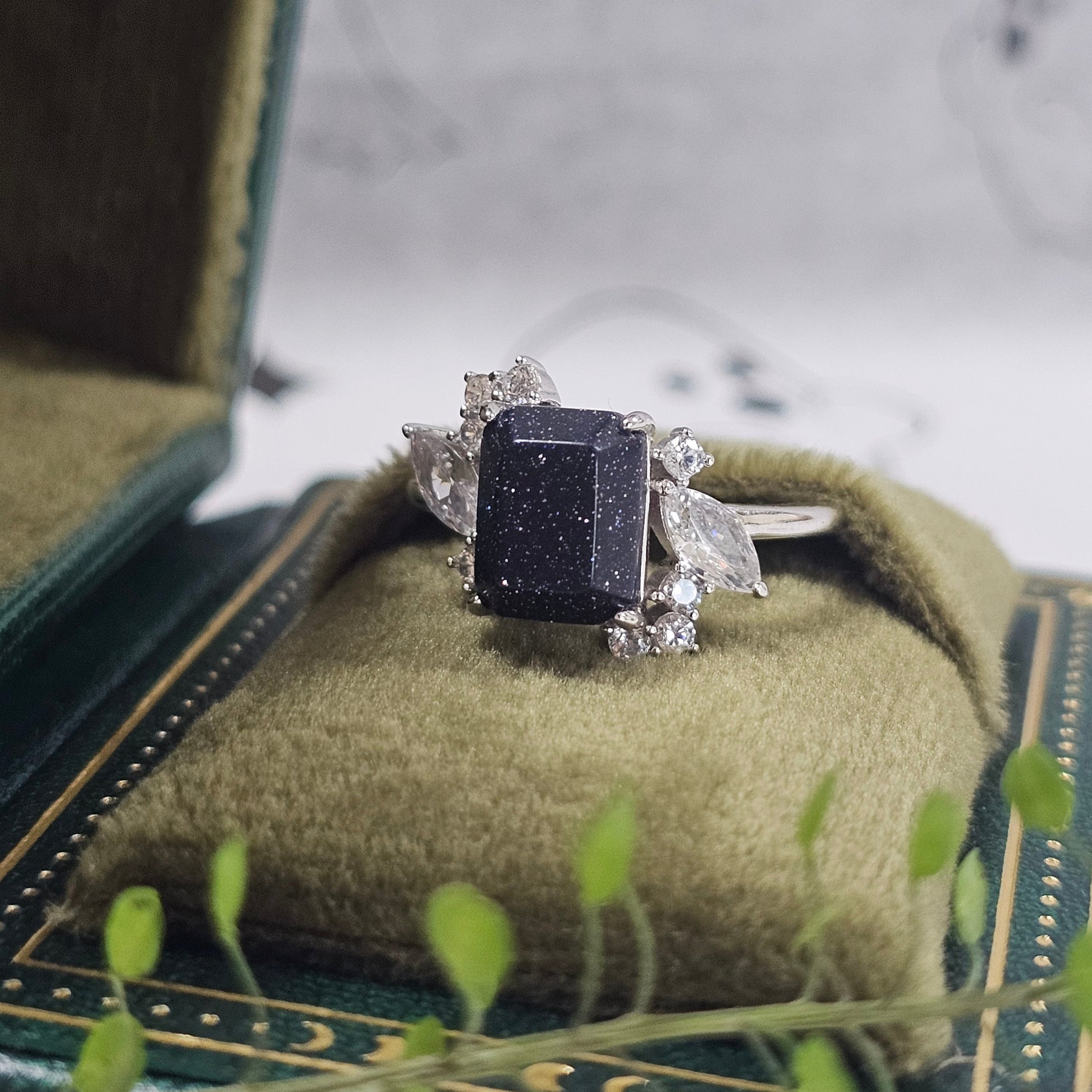 Silver ring with a black gemstone on a textured surface