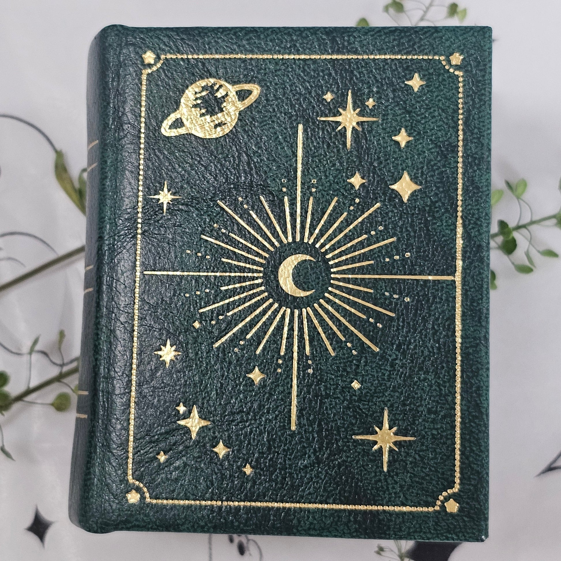 Green notebook with gold celestial designs on a light gray background