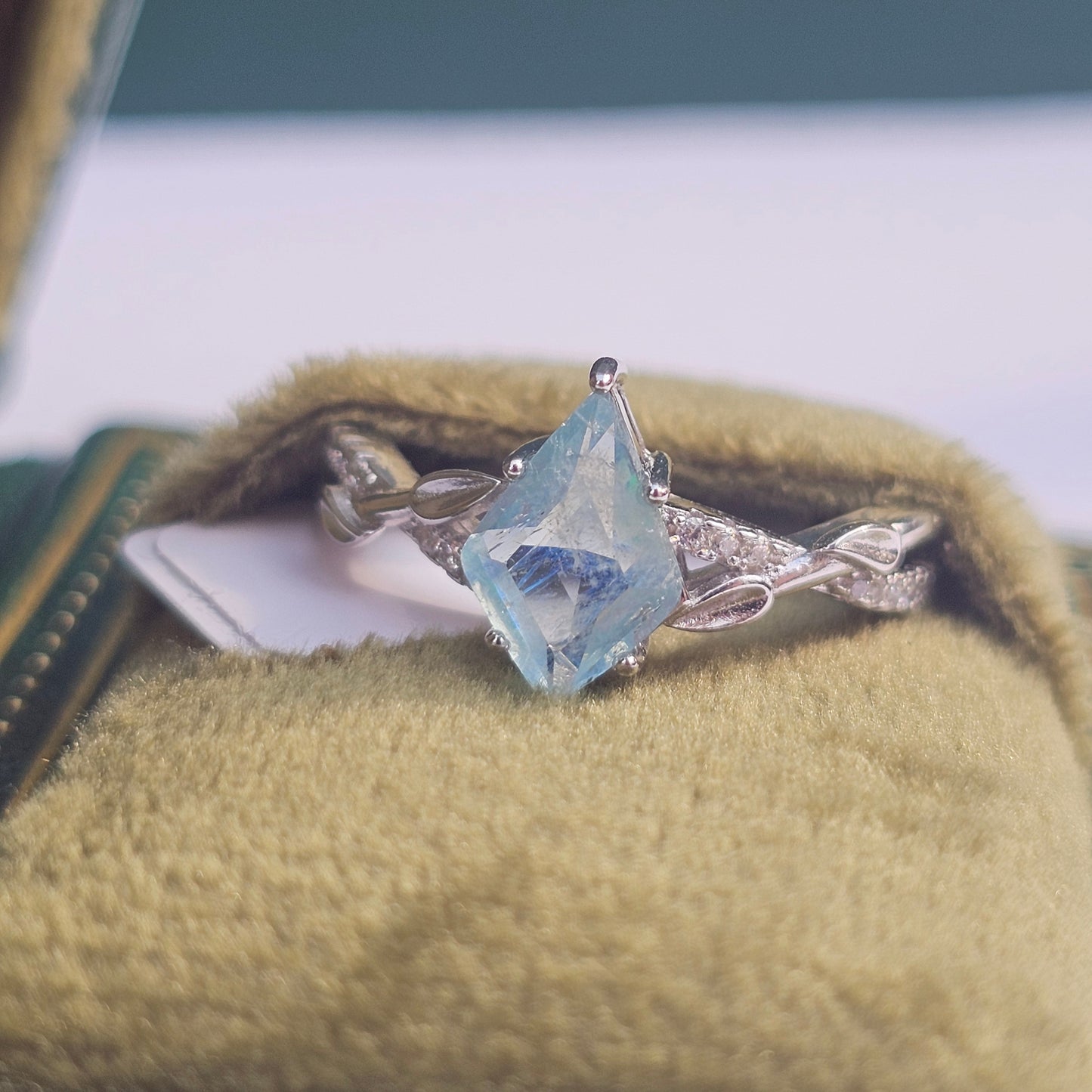 Silver pendant with a blue gemstone on a green cushion