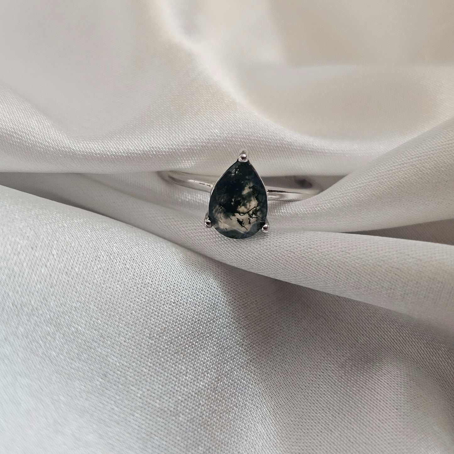 Silver ring with a black gemstone on a white fabric background