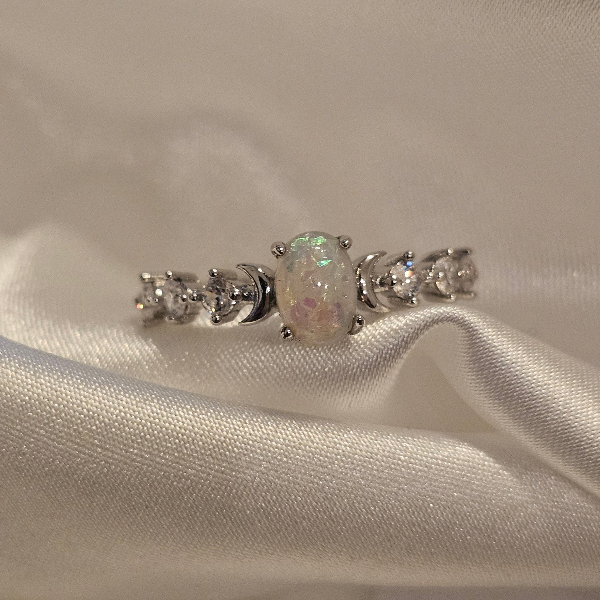 Silver earring with gemstones on a white fabric background opal