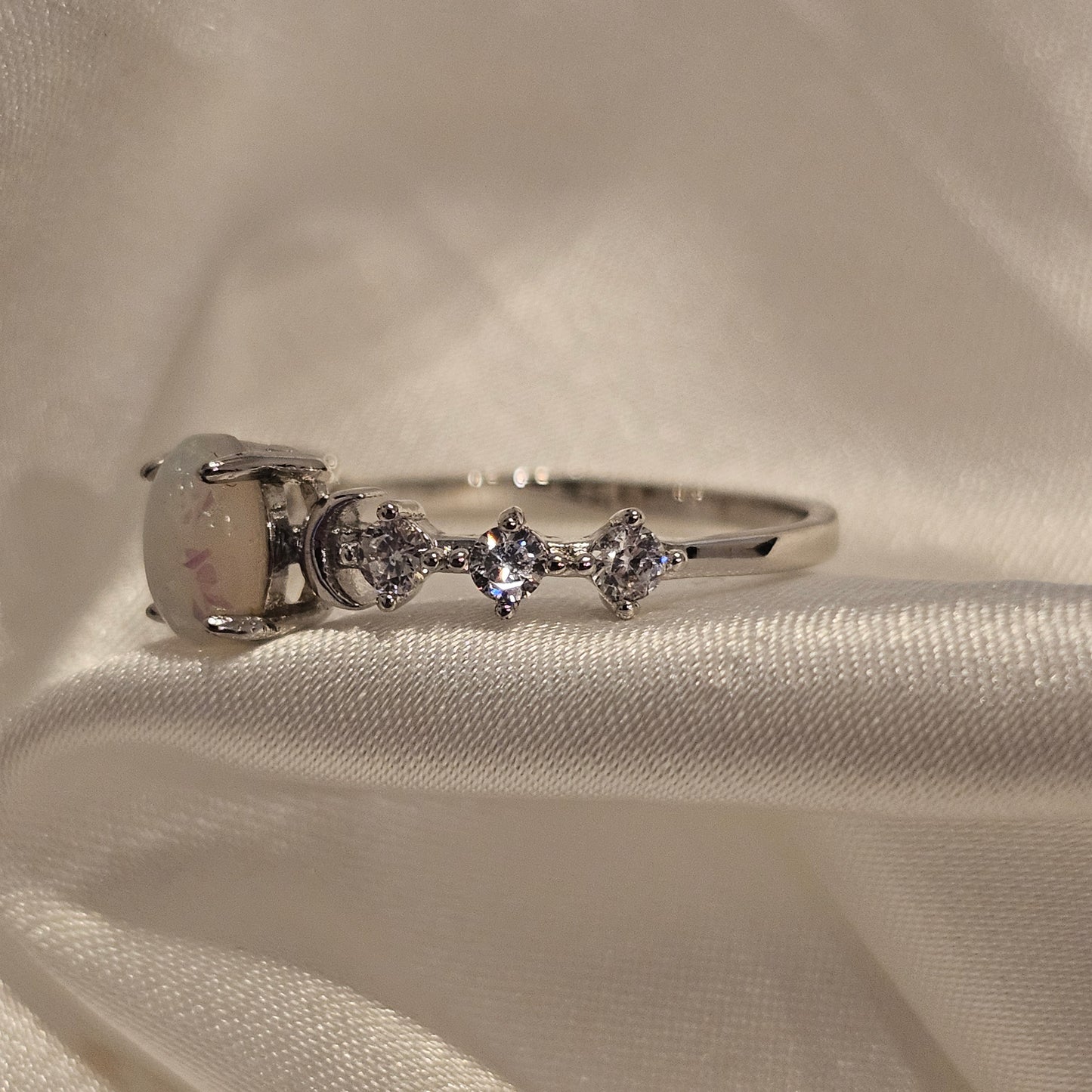 White multicolour opal ring with cubic zirconia accent stones sparkly gift idea on silk background