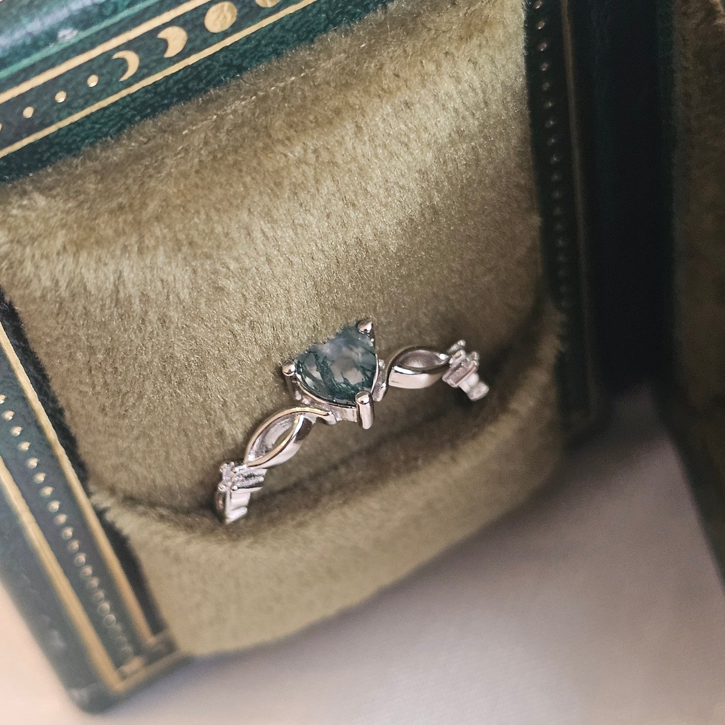 Evergreen Heart Ring — natural heart-cut Moss Agate solitaire in 925 sterling silver with infinity band, displayed in green velvet jewellery box.