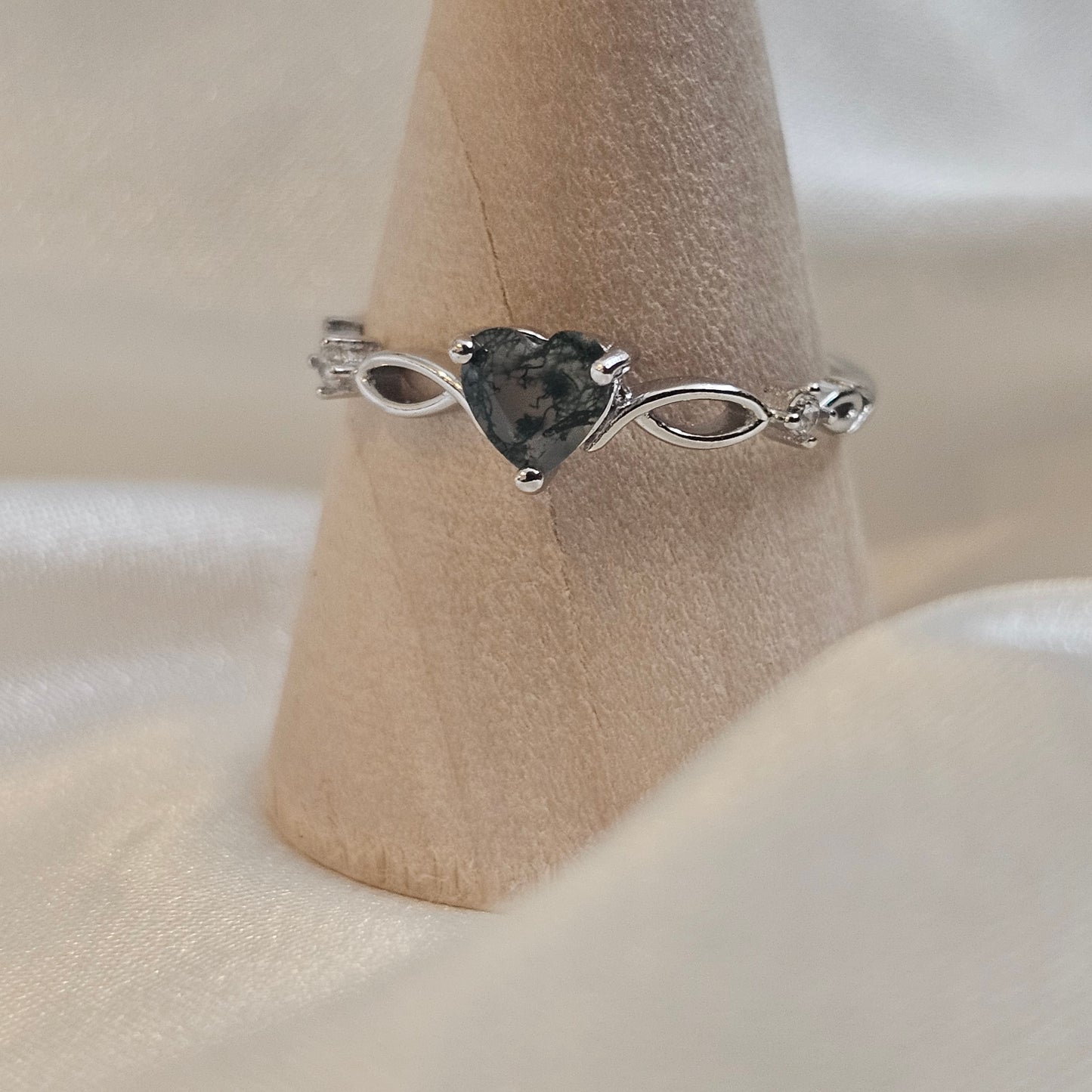 Heart-cut Moss Agate ring with infinity band in 925 sterling silver — Evergreen Heart Ring photographed on wooden ring cone.