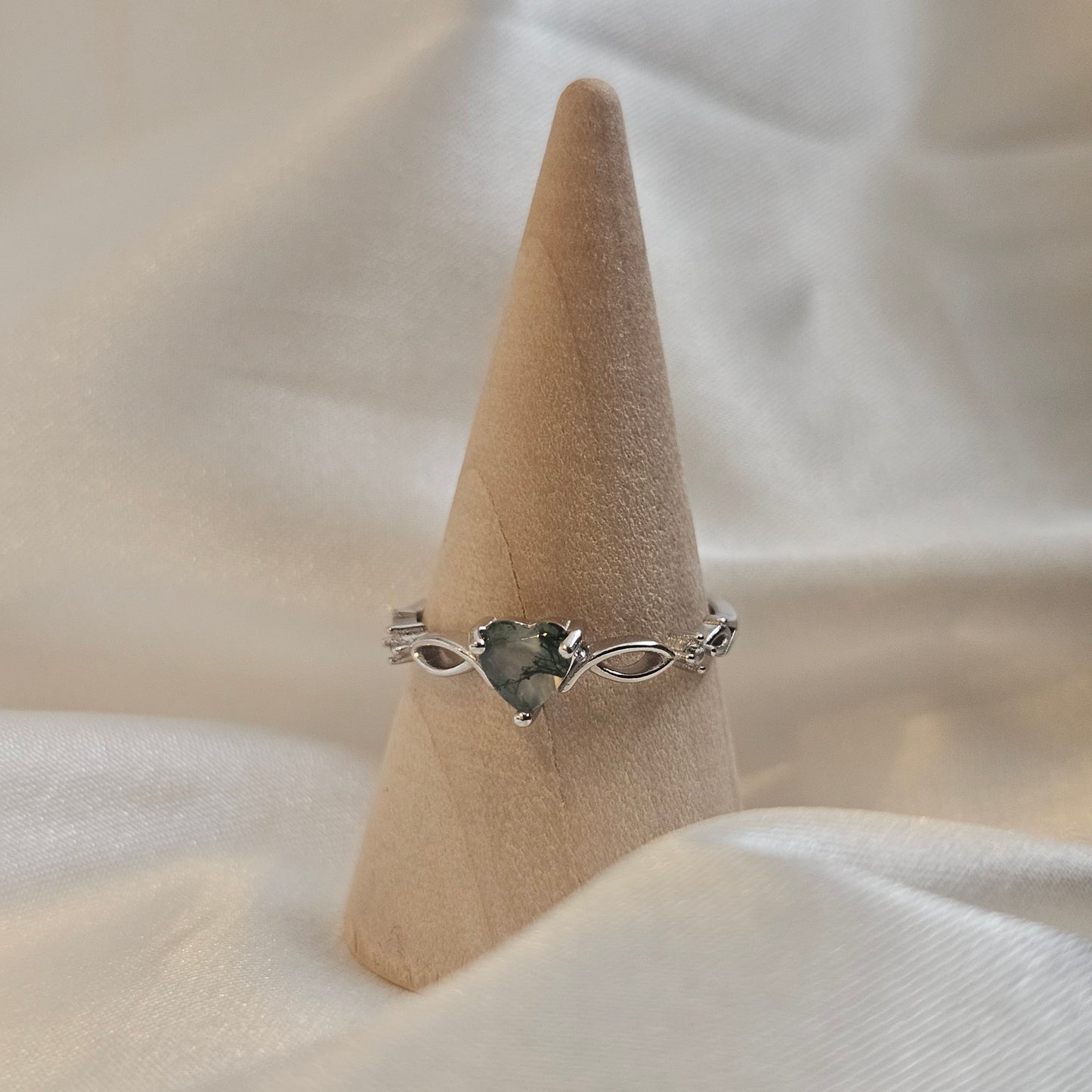 Heart-cut Moss Agate ring with infinity band in 925 sterling silver — Evergreen Heart Ring photographed on wooden ring cone.