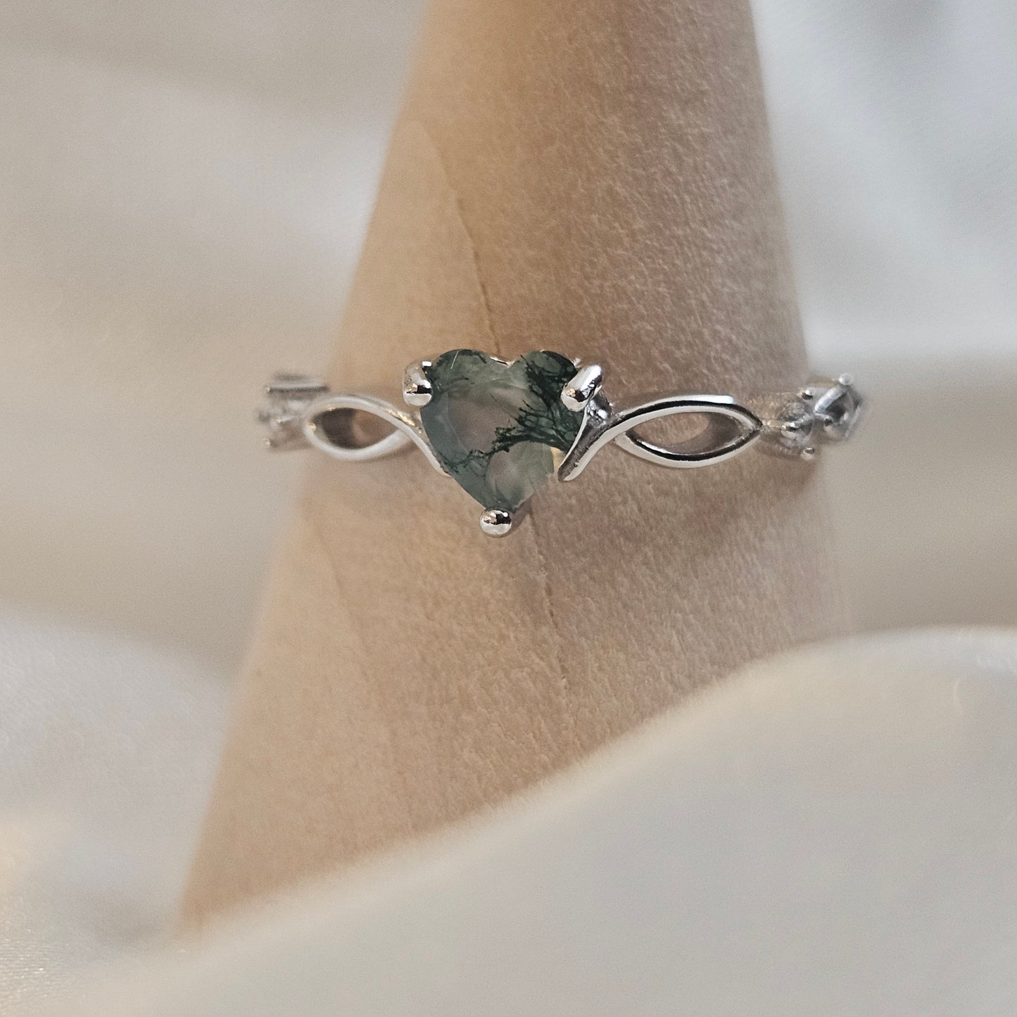 Heart-cut Moss Agate ring with infinity band in 925 sterling silver — Evergreen Heart Ring photographed on wooden ring cone.