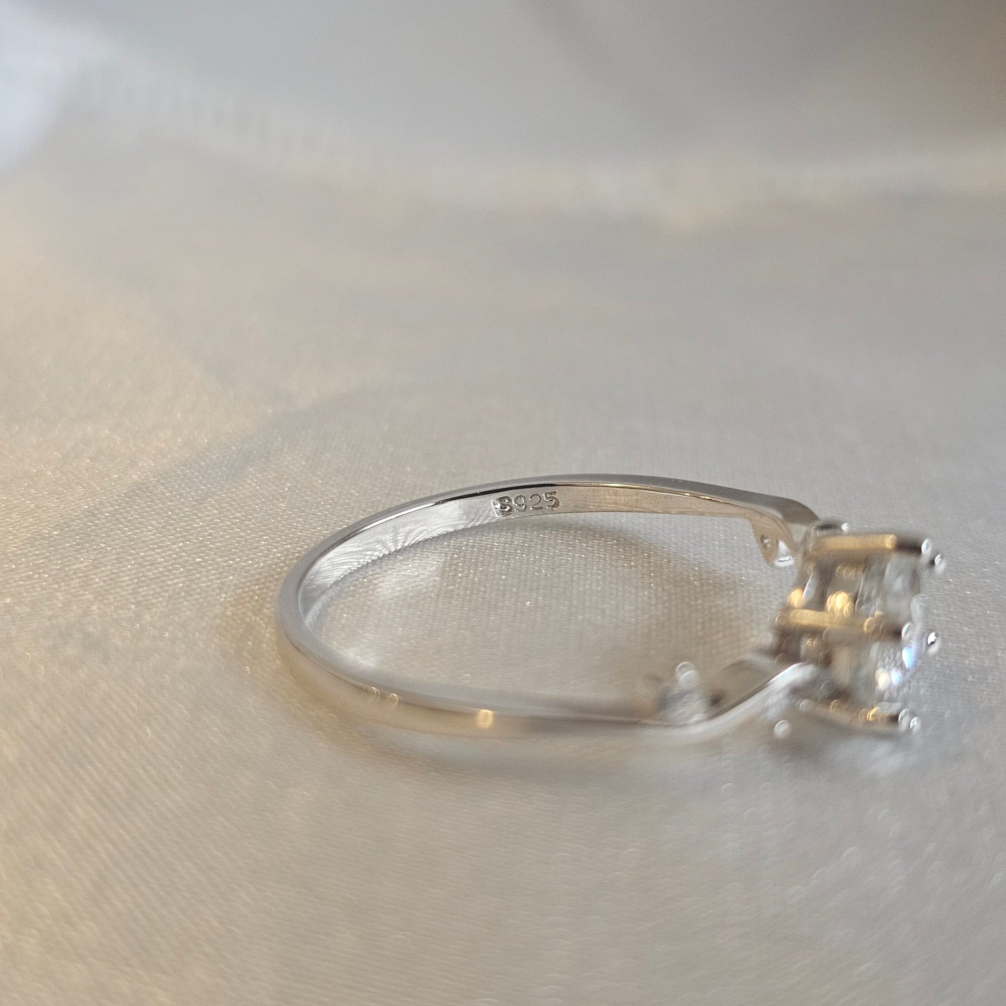 Silver ring with a diamond on a light gray background