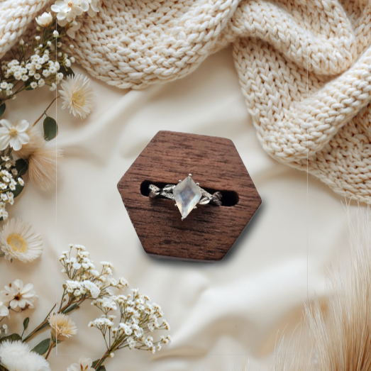Boho image of a wooden hexagonal box with a stunning natural moonstone ring on a soft beige fabric background with flowers.