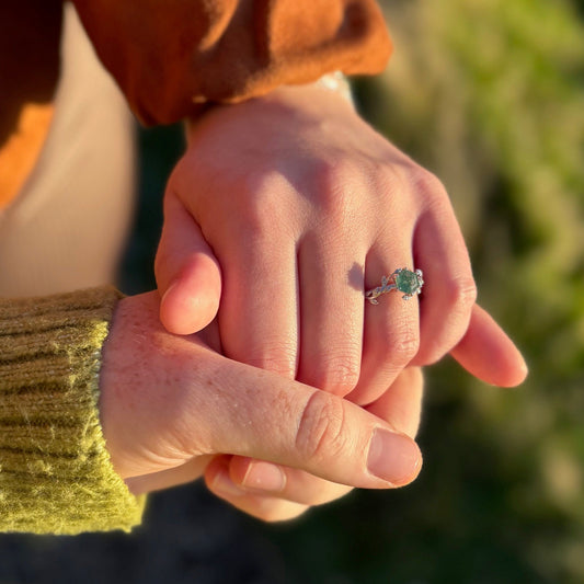 Two hands holding each other with a blurred natural background