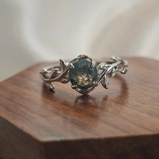 Silver ring with a green gemstone on a wooden surface