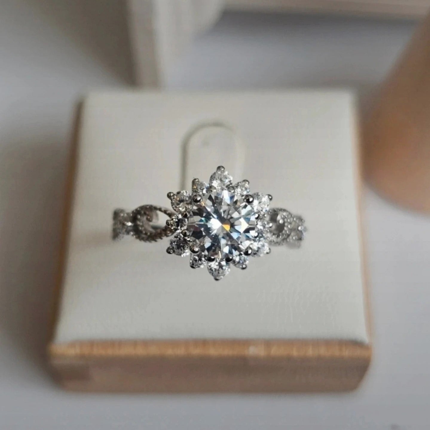 Silver ring with a diamond-like center on a wooden box