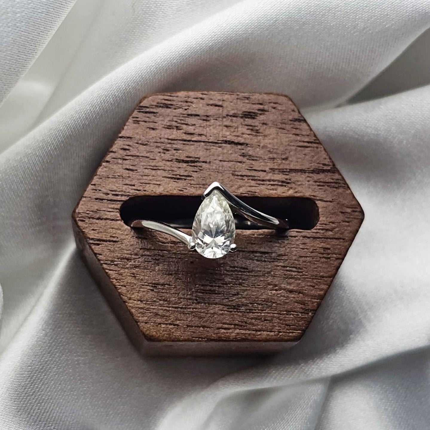 Diamond ring on a wooden hexagonal stand with white fabric background