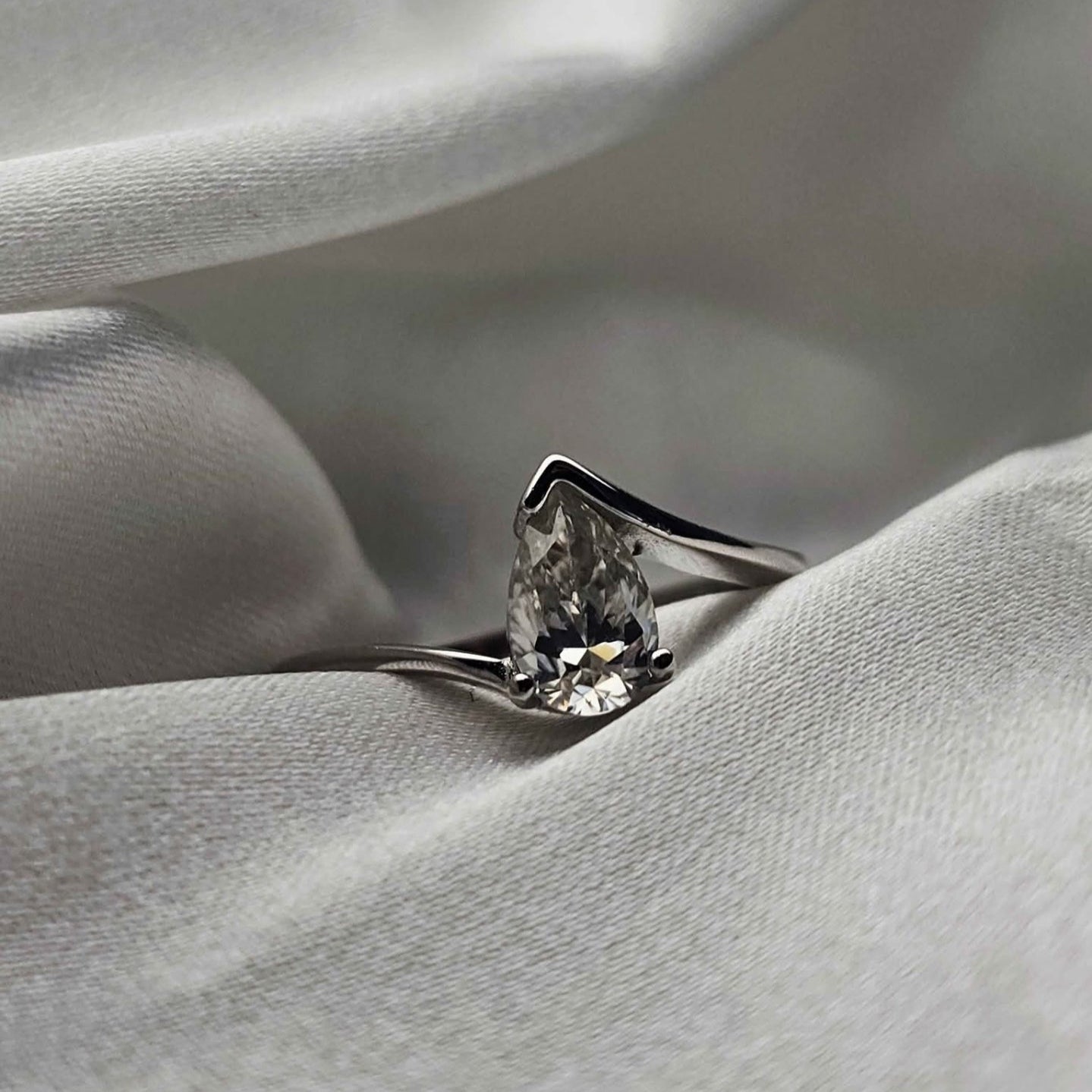 Diamond ring on a soft, light gray fabric background