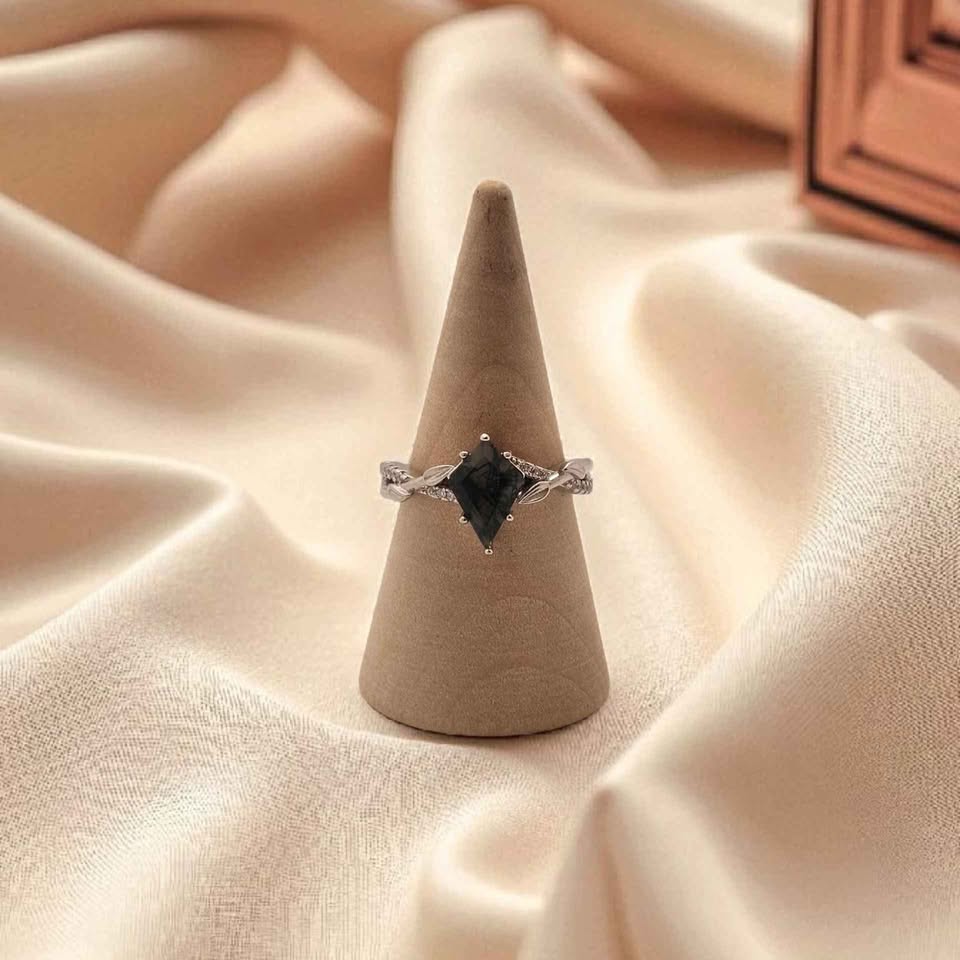 Kite cut Moss Agate ring with leaf detail and cubic zirconia in 925 sterling silver, displayed on ring cone with soft champagne fabric background
