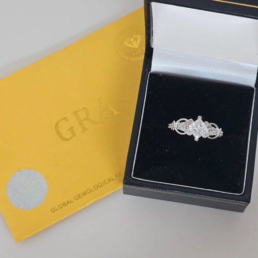 Moissanite sterling silver ring presented in black ring box next to yellow GRA certificate card
