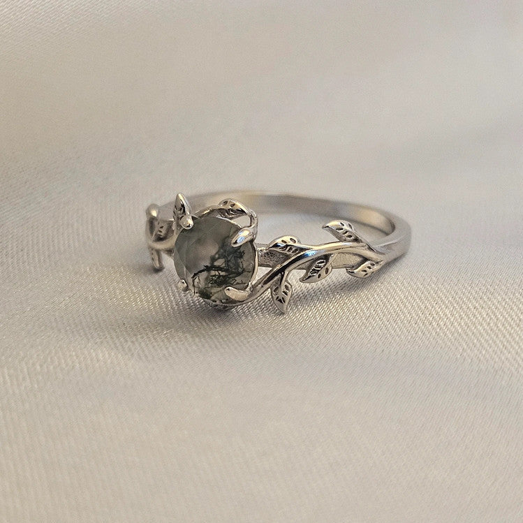 Silver 925 moss agate ring with leaf detail, botanical with a textured stone on a beige fabric background