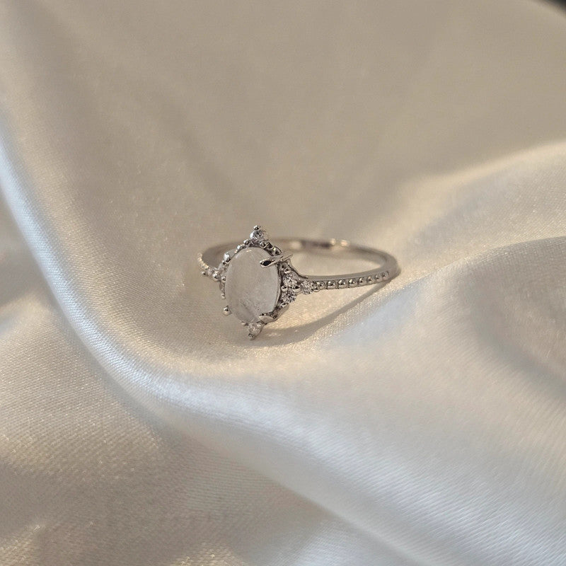 Silver ring with a moon stone on a light fabric background