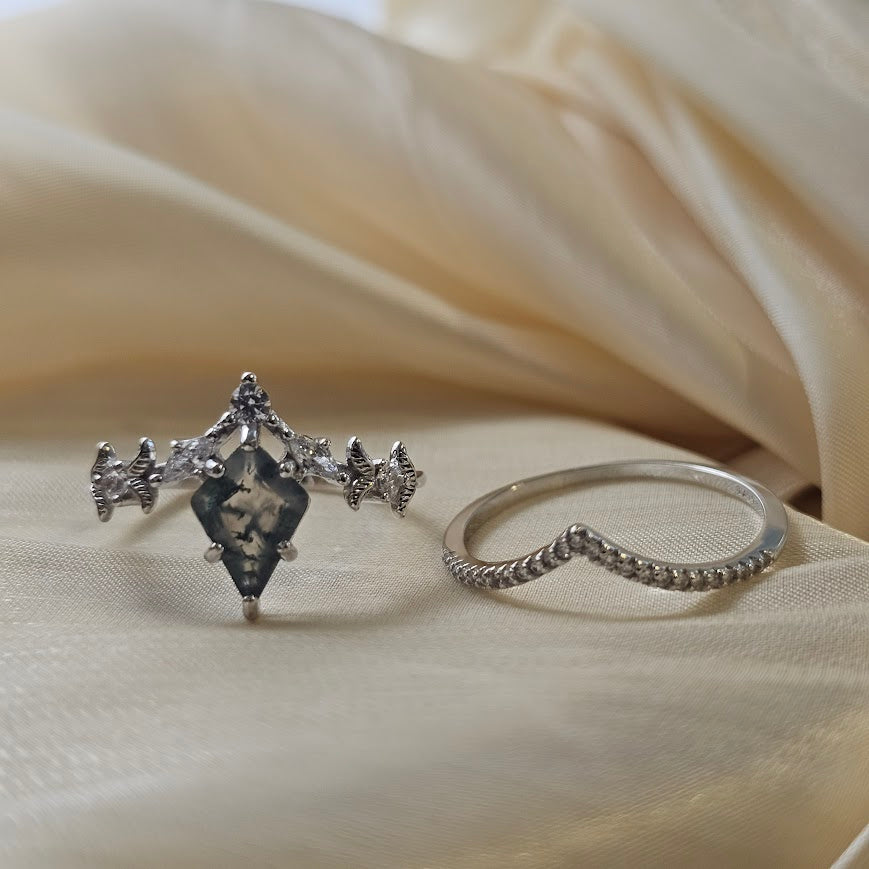 Moss agate engagement ring with crown band displayed side by side on beige satin fabric background
