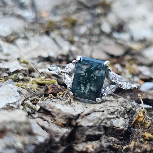 Silver ring with a greenish stone on a textured surface