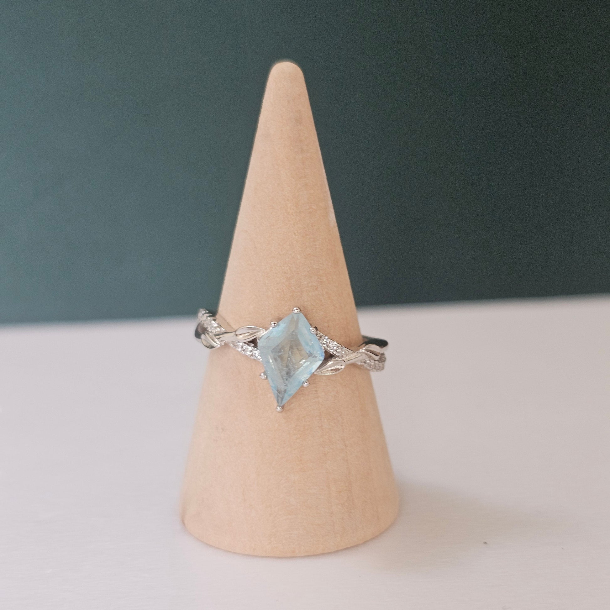 Silver ring with a blue gemstone on a wooden cone against a dark background