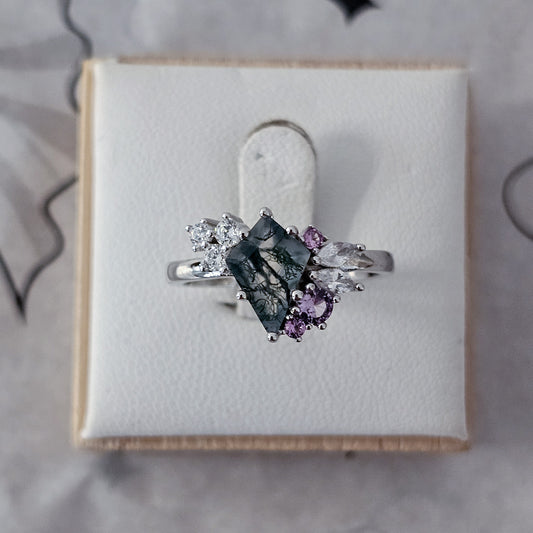 Silver ring with gemstones on a white cushion in a box
