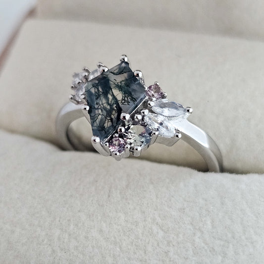 Silver ring with a natural moss agate gemstone and smaller pink stones on a beige cushion