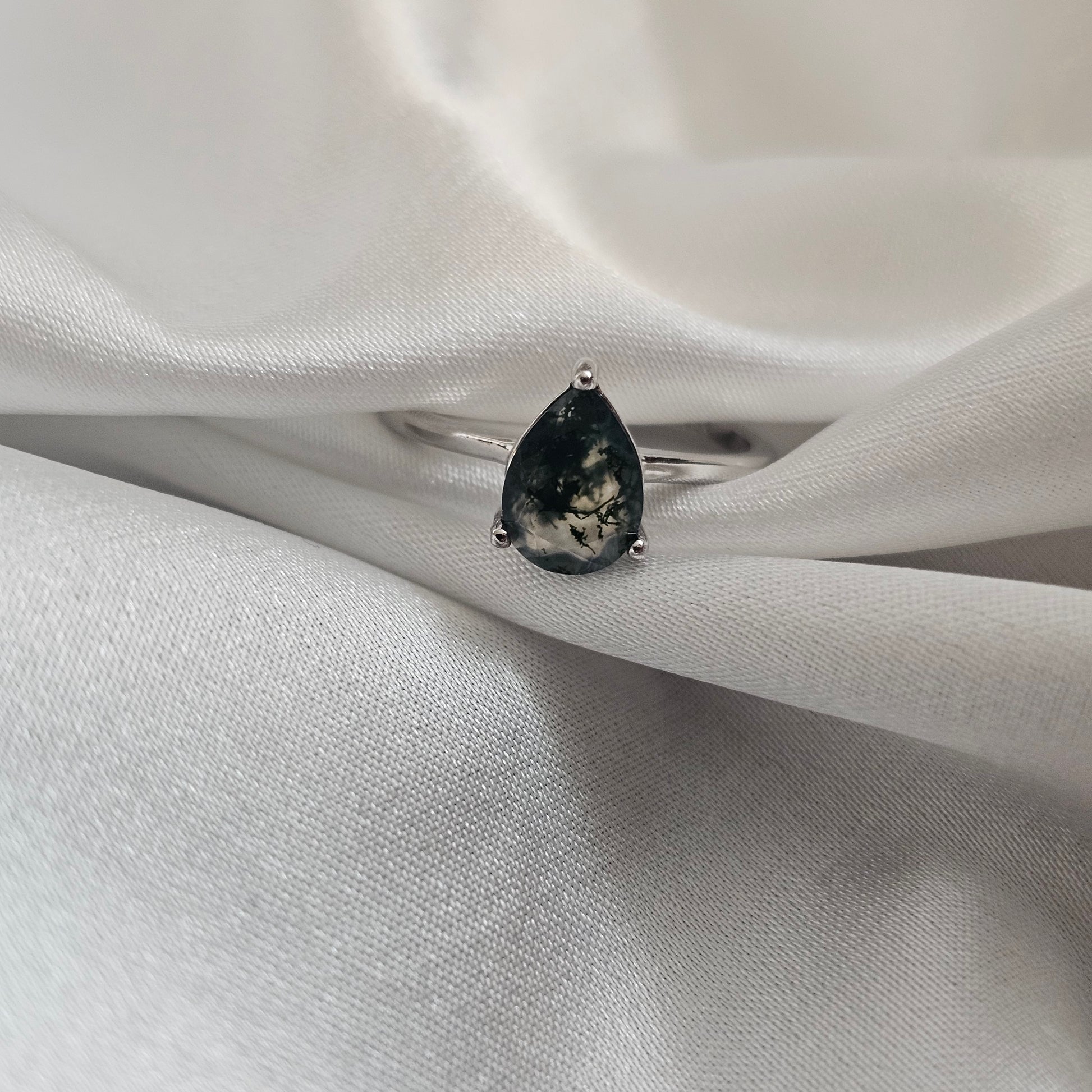 Silver ring with a black gemstone on a white fabric background