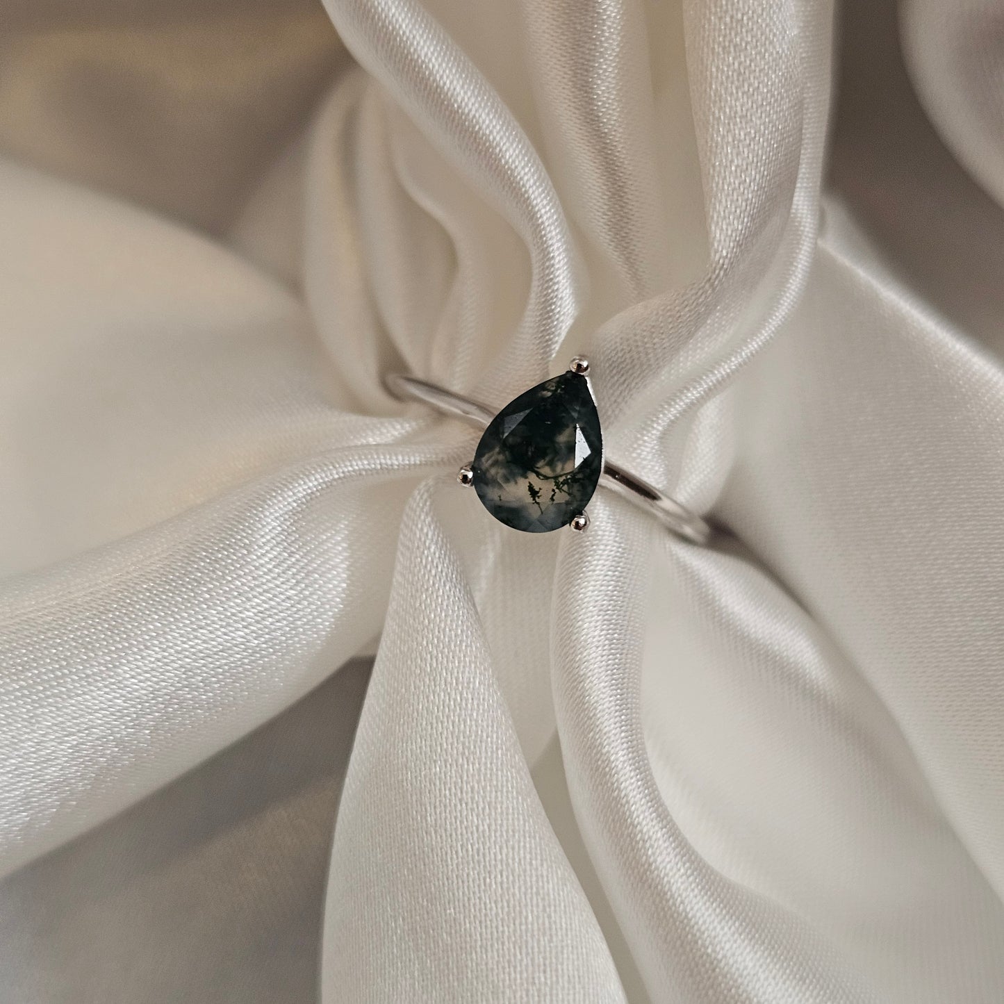 Ring with a black gemstone on a white satin background