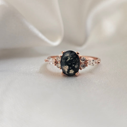 Ring with a moss agate stone and rose gold setting on a white fabric background