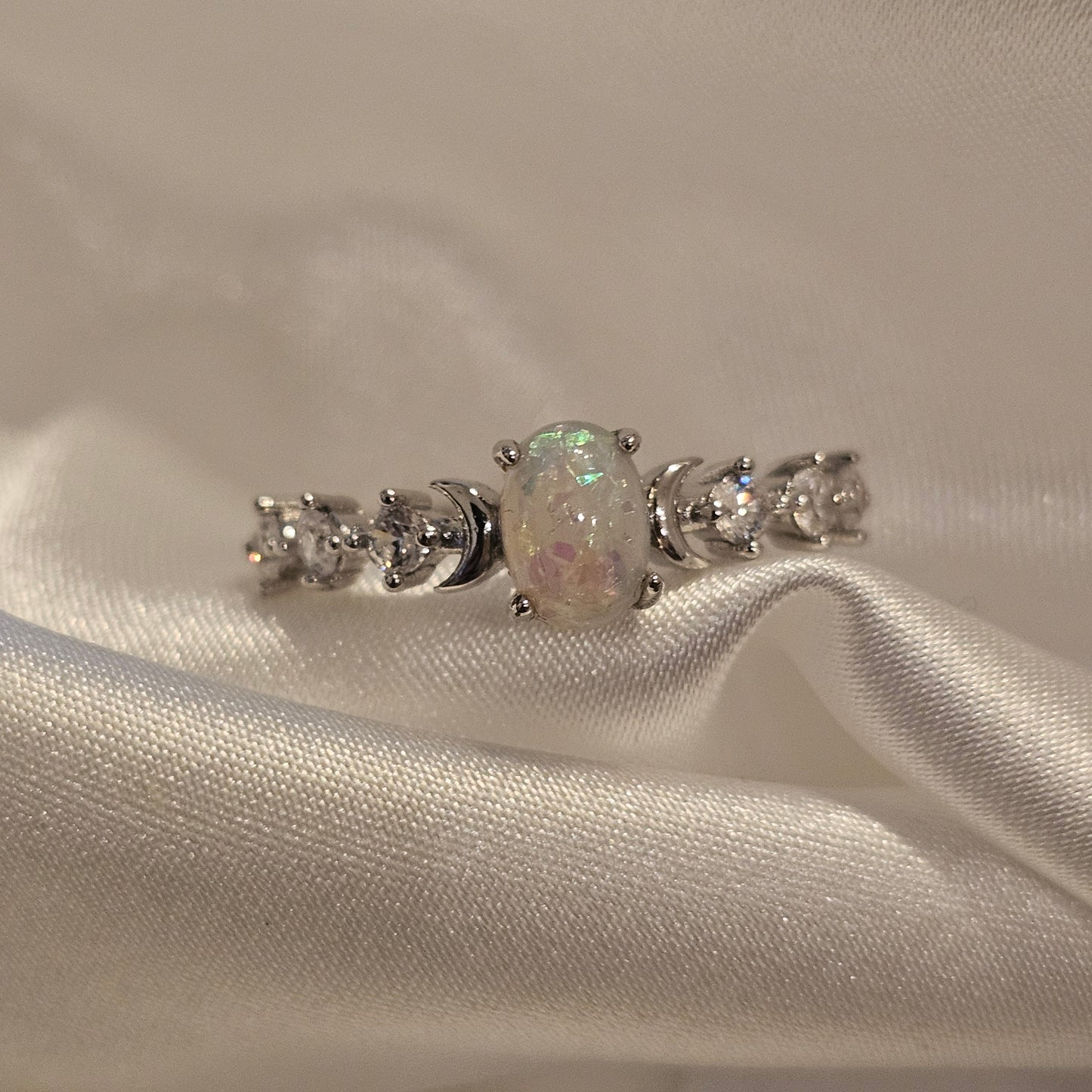 Silver earring with gemstones on a white fabric background opal