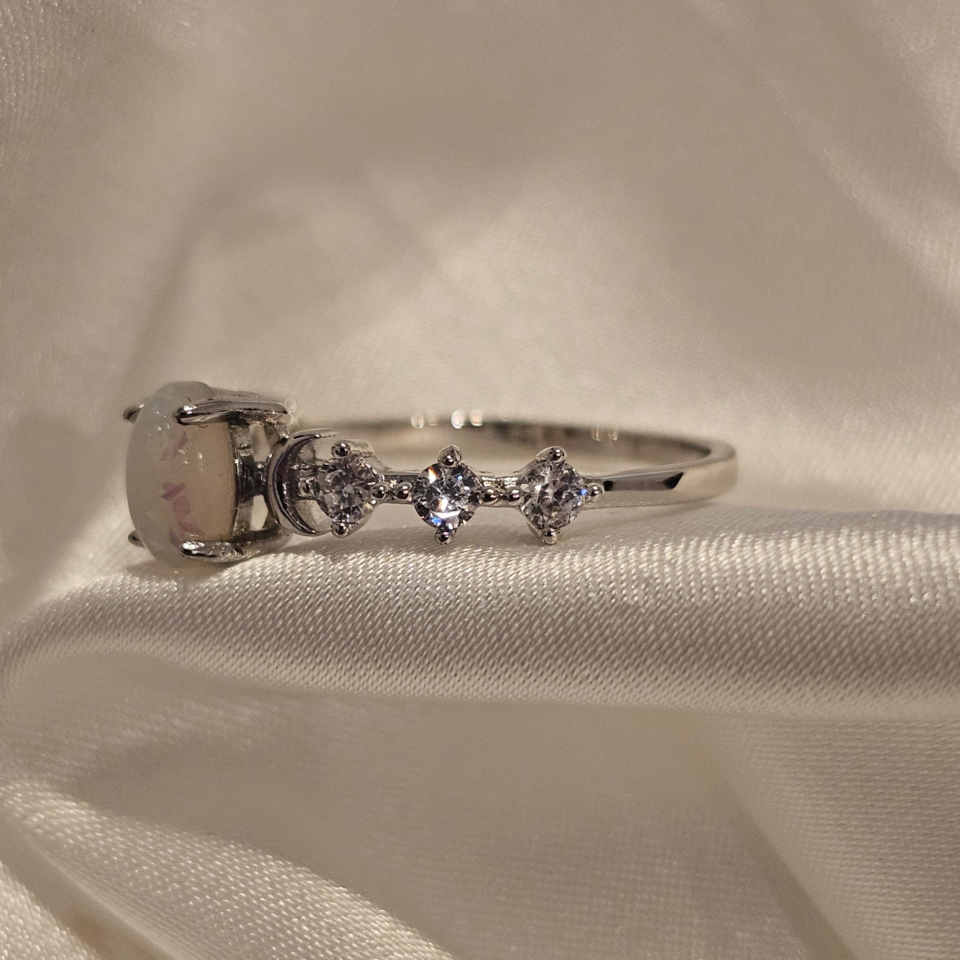 White multicolour opal ring with cubic zirconia accent stones sparkly gift idea on silk background 