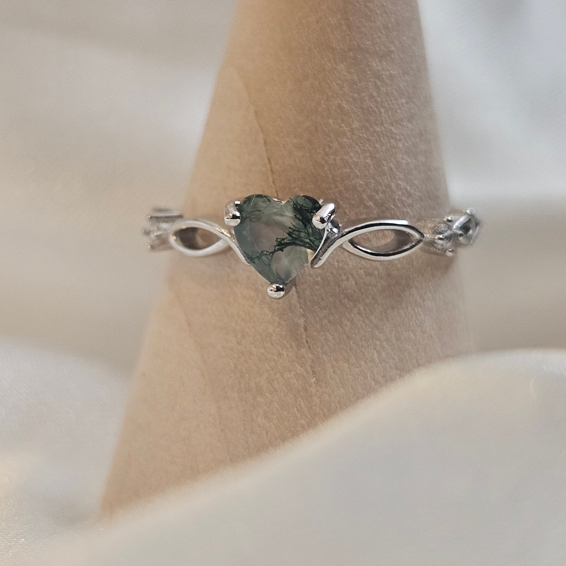 Heart-cut Moss Agate ring with infinity band in 925 sterling silver — Evergreen Heart Ring photographed on wooden ring cone.